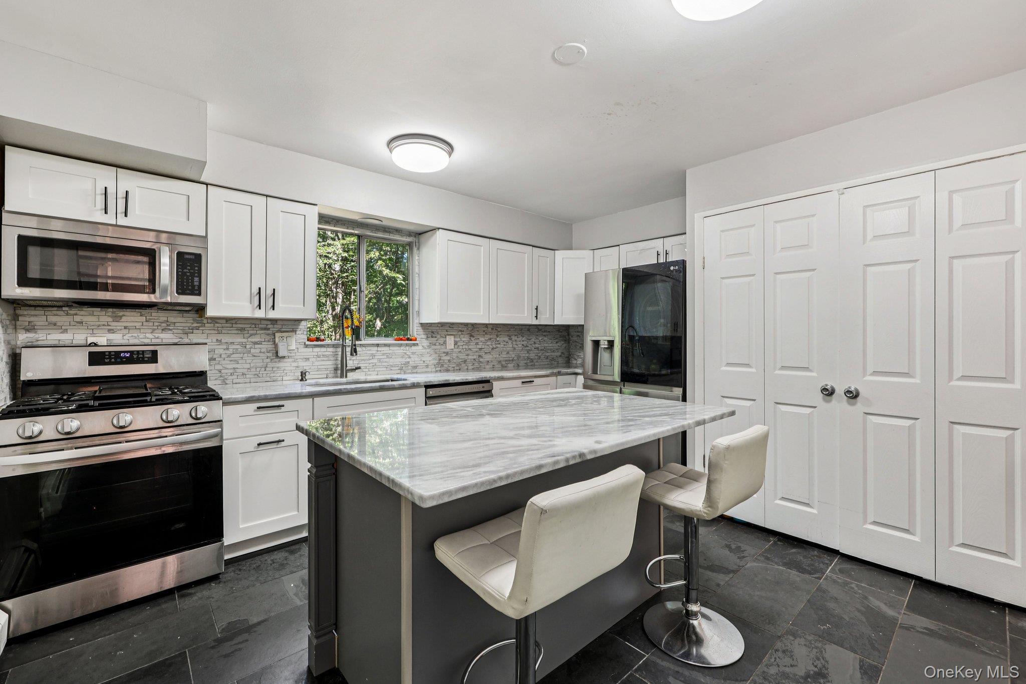 9 Crane Road Middletown, NY 10941 - Photo 11 of 31 Kitchen with appliances with stainless steel finishes, a kitchen breakfast bar, white cabinets, light stone counters, and tasteful backsplash