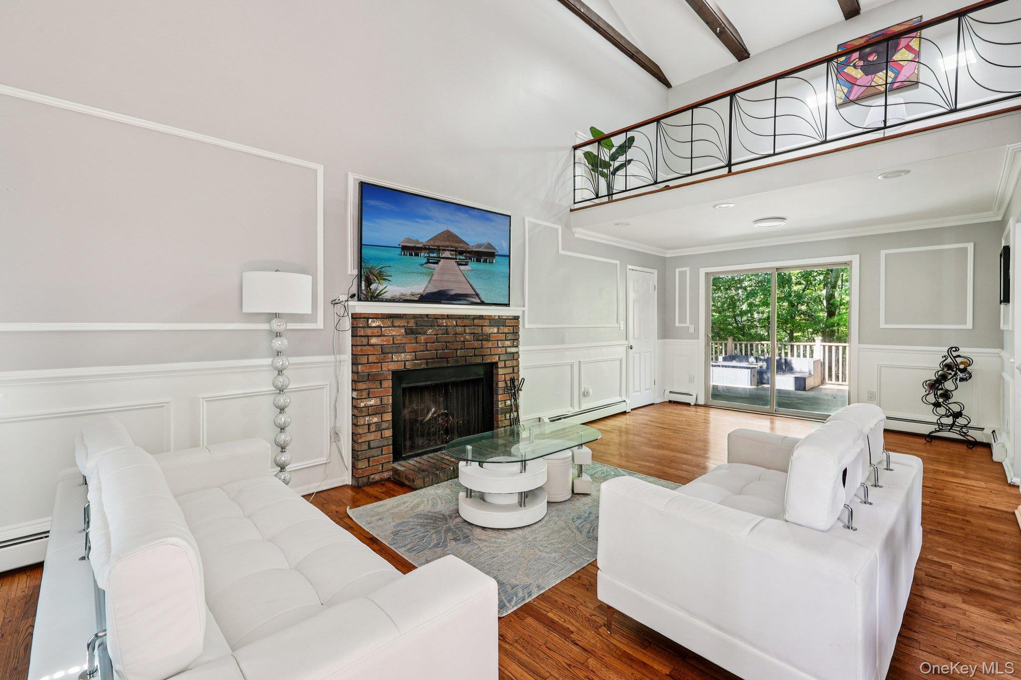 9 Crane Road Middletown, NY 10941 - Photo 2 of 31 Living room with a brick fireplace, wood finished floors, high vaulted ceiling, and wainscot walls