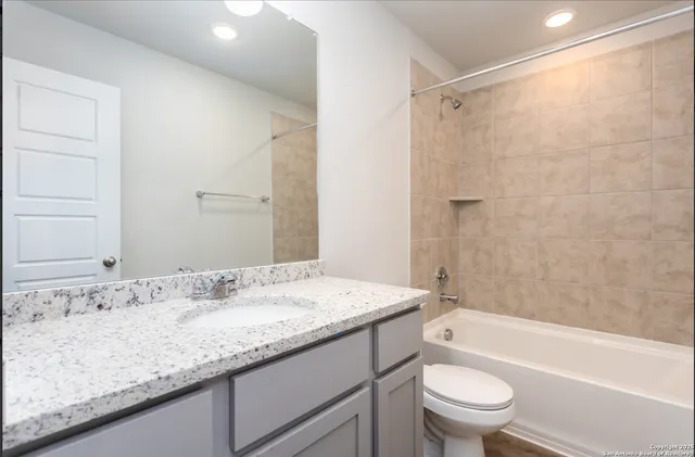 a bathroom with a granite countertop sink a toilet and shower