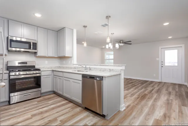 a kitchen with kitchen island granite countertop a sink cabinets and stainless steel appliances