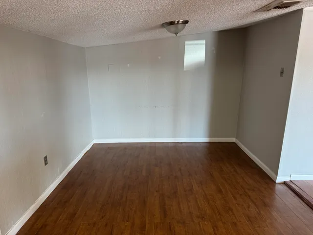 an empty room with wooden floor fireplace and windows