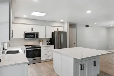 a kitchen with a sink a stove a refrigerator and white cabinets
