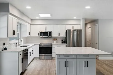 a kitchen with stainless steel appliances a sink stove refrigerator and cabinets