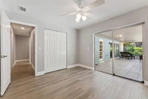 an empty room with wooden floor and way to kitchen