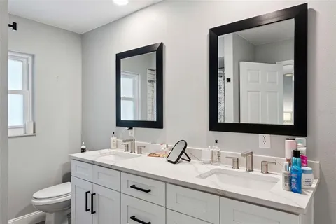a bathroom with a granite countertop sink a toilet and a mirror