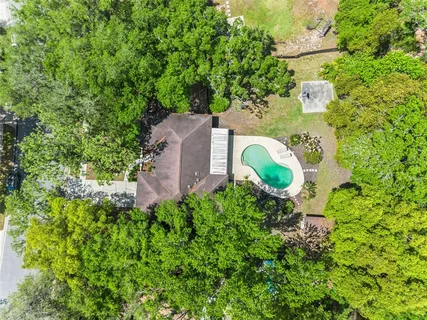 a aerial view of a house with a swimming pool and large trees