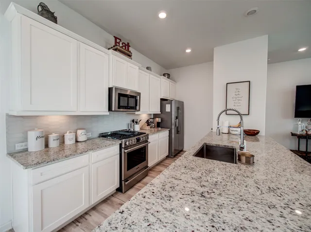 a kitchen with granite countertop a stove sink and a refrigerator
