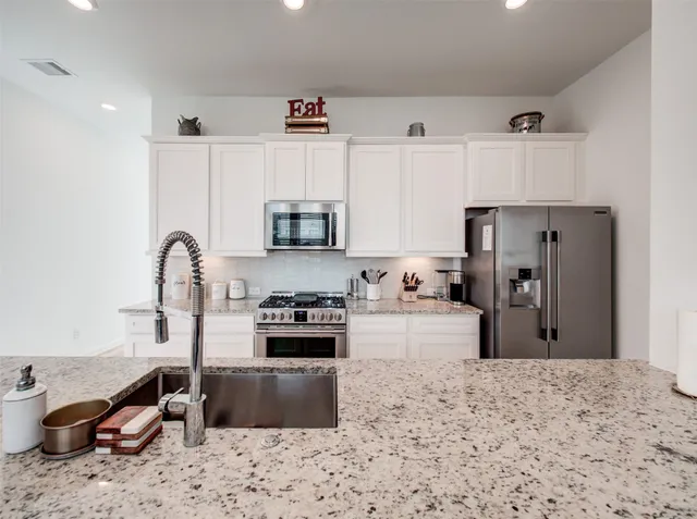 a kitchen with stainless steel appliances granite countertop a sink a stove and refrigerator