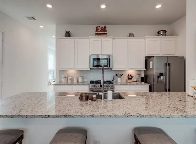 a kitchen with stainless steel appliances granite countertop a sink a stove and a microwave