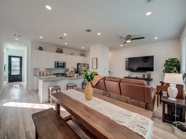 a living room with stainless steel appliances furniture a flat screen tv and kitchen view