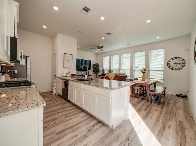 a large kitchen with stainless steel appliances granite countertop a lot of counter space and wooden floor
