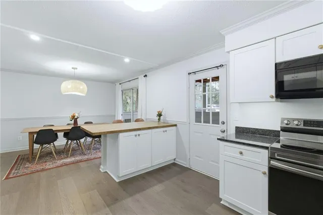 a large white kitchen with a sink and dishwasher a stove top oven with wooden floor