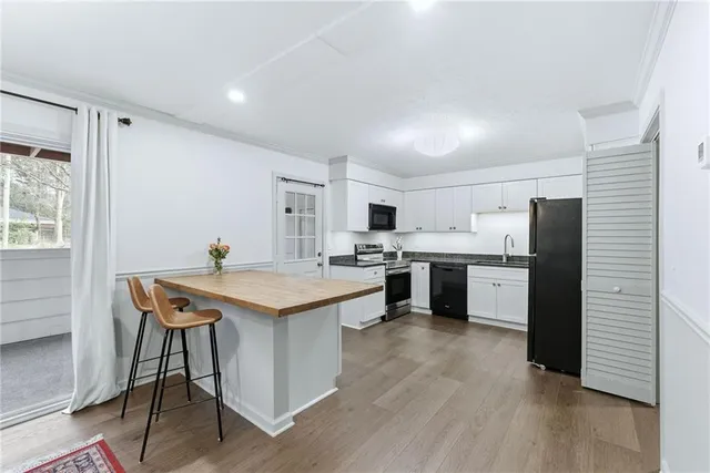 a kitchen with stainless steel appliances kitchen island granite countertop a sink cabinets and wooden floor