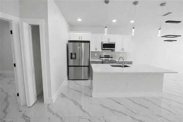 a kitchen with stainless steel appliances kitchen island granite countertop a refrigerator and a stove top oven