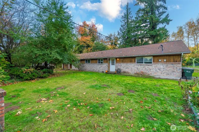 a view of a house with a yard plants and large tree