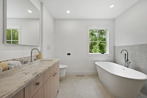 a bathroom with a granite countertop sink a toilet and a bathtub