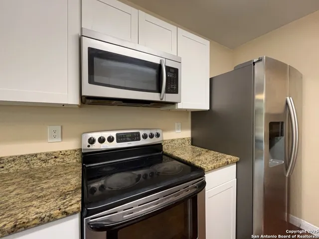 a kitchen with granite countertop a stove microwave and fridge