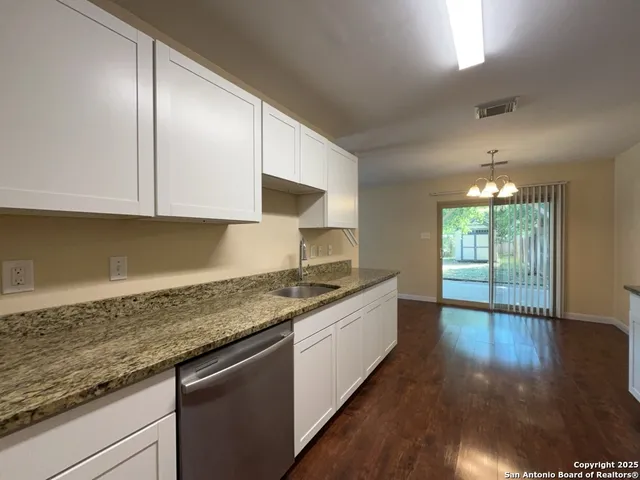 a kitchen with granite countertop wooden cabinets a sink and dishwasher