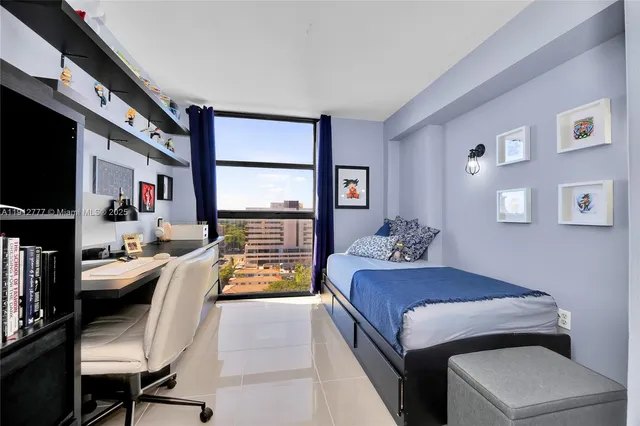 a bedroom with a bed couch and a flat tv screen next to a window