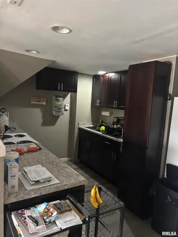 a kitchen with stainless steel appliances kitchen island granite countertop a refrigerator a stove and a sink with wooden floor