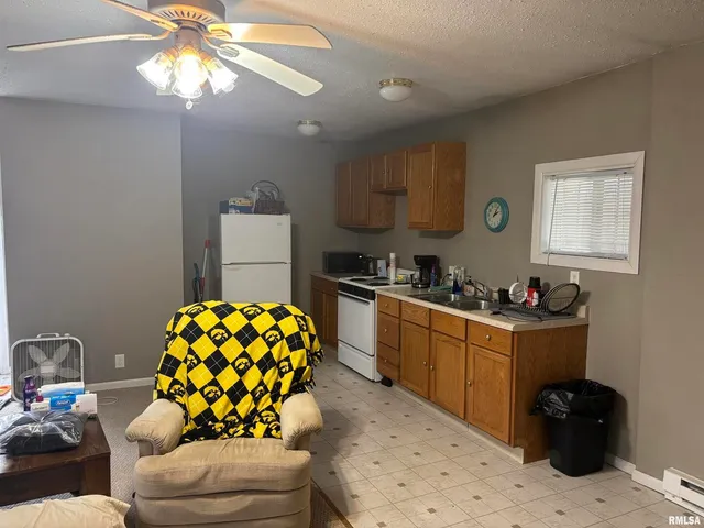 a kitchen with stainless steel appliances kitchen island granite countertop a sink a stove white cabinets a dining table and chairs with wooden floor