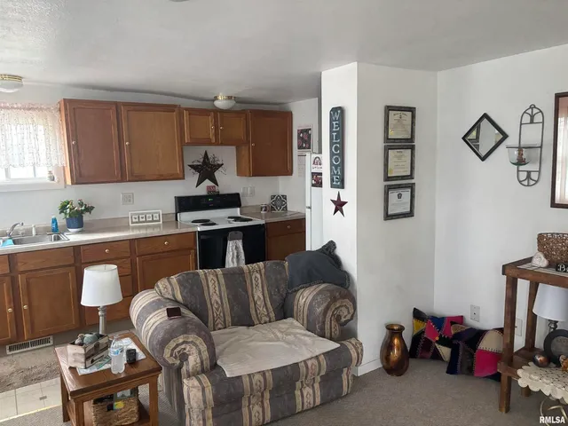 a living room with furniture kitchen view and a window