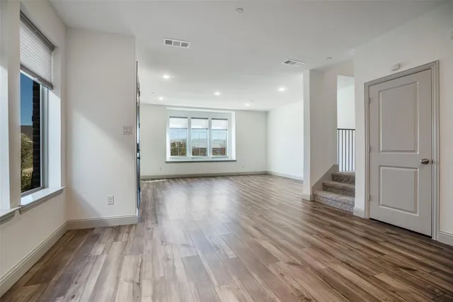 an empty room with wooden floor and windows