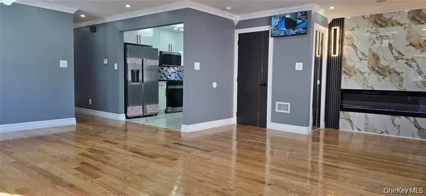 a view of a hallway with wooden floor and a bathroom
