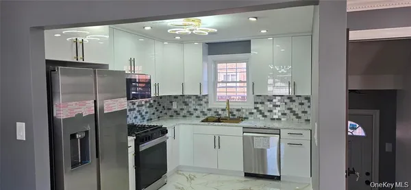 a kitchen with stainless steel appliances kitchen island granite countertop a refrigerator and a sink