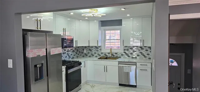 a kitchen with stainless steel appliances kitchen island granite countertop a refrigerator and a sink