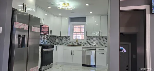 a kitchen with stainless steel appliances kitchen island granite countertop a refrigerator and a sink