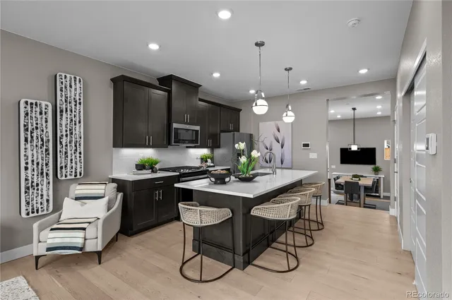 a kitchen with stainless steel appliances kitchen island granite countertop a table chairs and a refrigerator