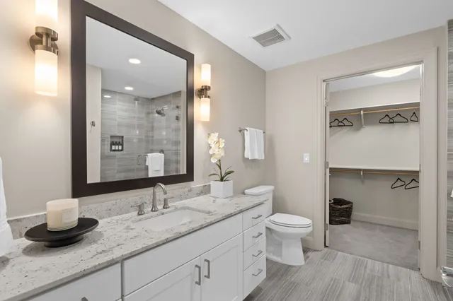 a bathroom with a granite countertop sink a toilet and a mirror