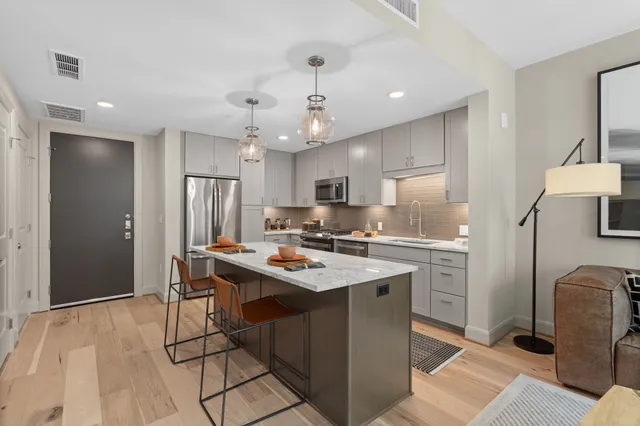 a kitchen with stainless steel appliances granite countertop a sink a stove a refrigerator cabinets and living room view