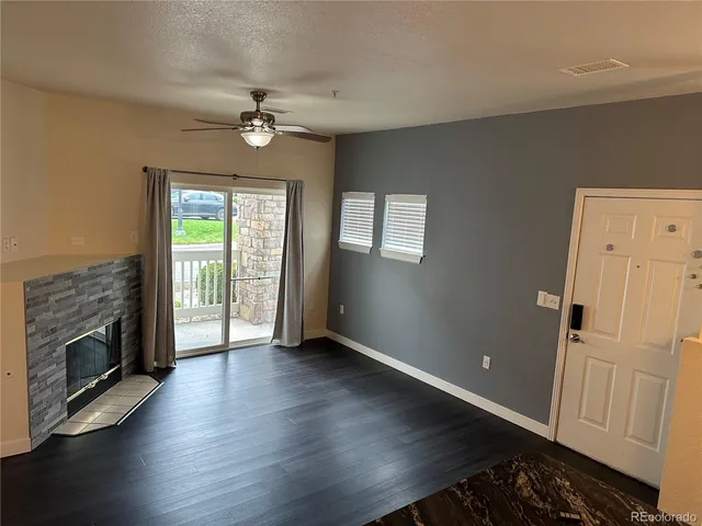 an empty room with wooden floor fireplace and windows