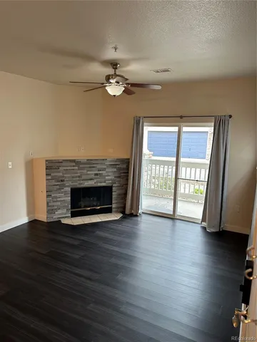 a view of an empty room with wooden floor fireplace and a window