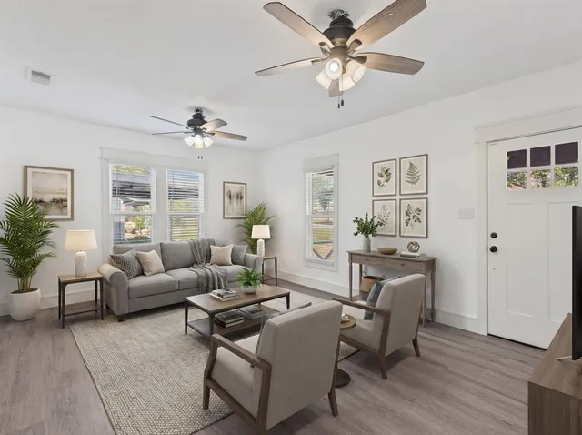 a living room with furniture a chandelier fan and a window