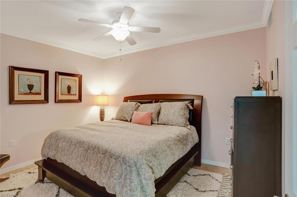 9731 Acqua Court, Unit 523 Naples, FL 34113 - Photo 11 of 27 a bedroom with a bed and a chandelier