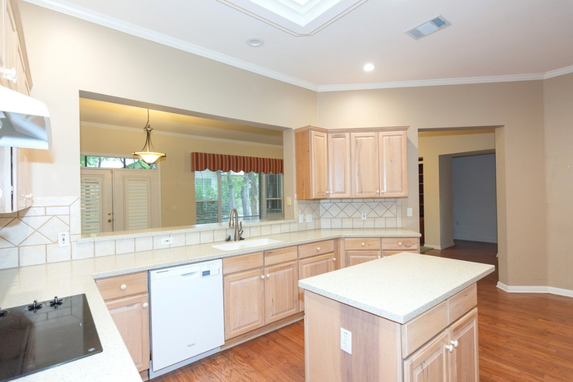 102 Harness Lane Georgetown, TX 78633 - Photo 13 of 32 Kitchen with light brown cabinetry, light wood-style flooring, ornamental molding, decorative backsplash, and black electric stovetop