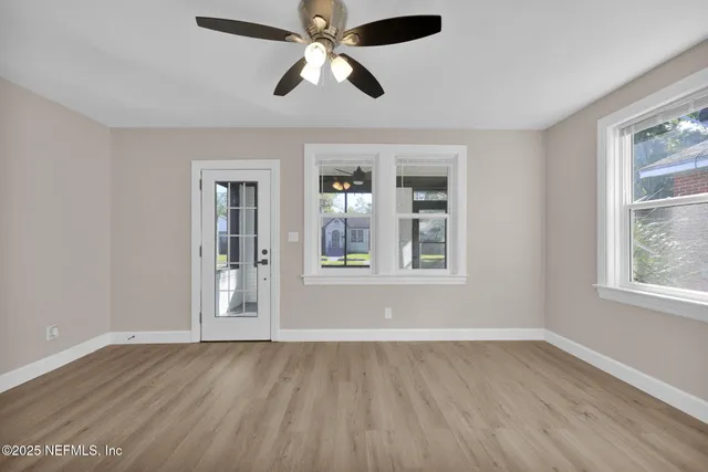 a view of an empty room with wooden floor and a window