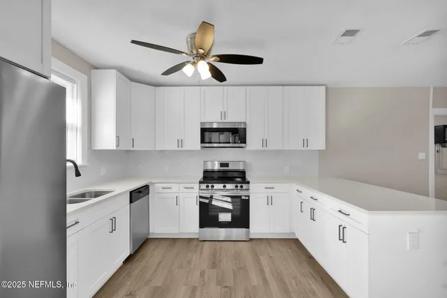 a kitchen with cabinets stainless steel appliances and a window