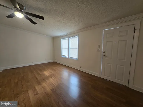 an empty room with wooden floor fan and windows