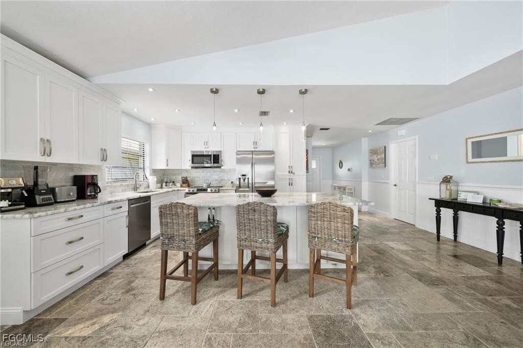 521 102nd Avenue North Naples, FL 34108 - Photo 13 of 25 a kitchen with stainless steel appliances kitchen island granite countertop a table chairs sink and cabinets