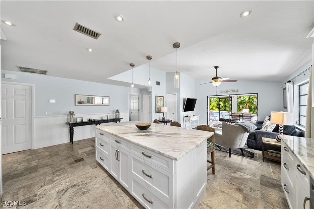 521 102nd Avenue North Naples, FL 34108 - Photo 10 of 25 a large kitchen with kitchen island a stove a sink a dining table and chairs