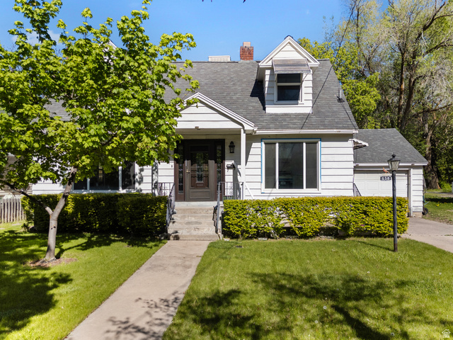 White siding residence featuring a dark front door, a dormer window, and an attached garage