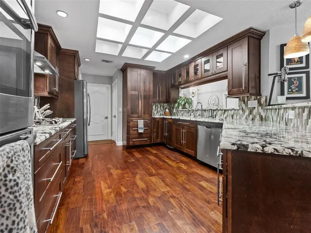 a kitchen with stainless steel appliances granite countertop a sink a stove and cabinets