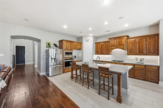 a kitchen with stainless steel appliances granite countertop a stove top oven a sink dishwasher a dining table and chairs with wooden floor