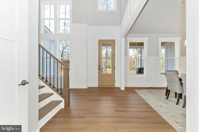 a view of an entryway with wooden floor leading to a furnished livingroom and windows