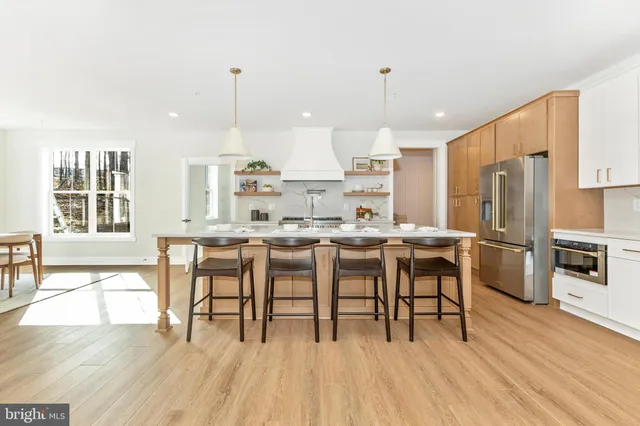a kitchen with stainless steel appliances a dining table chairs stove and refrigerator