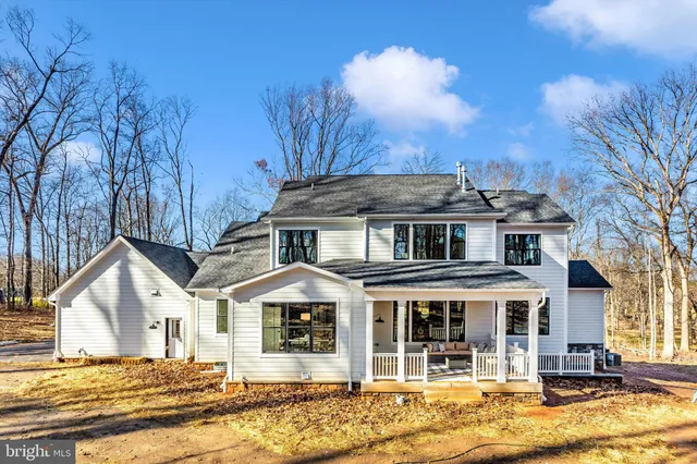 a front view of a house with a yard covered with snow and trees